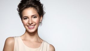 Naturally beautiful woman smiling with a tan tank top and brown hair-porcleain veneers