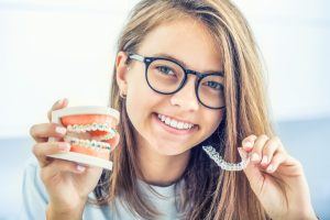 teen holding aligner and model of braces